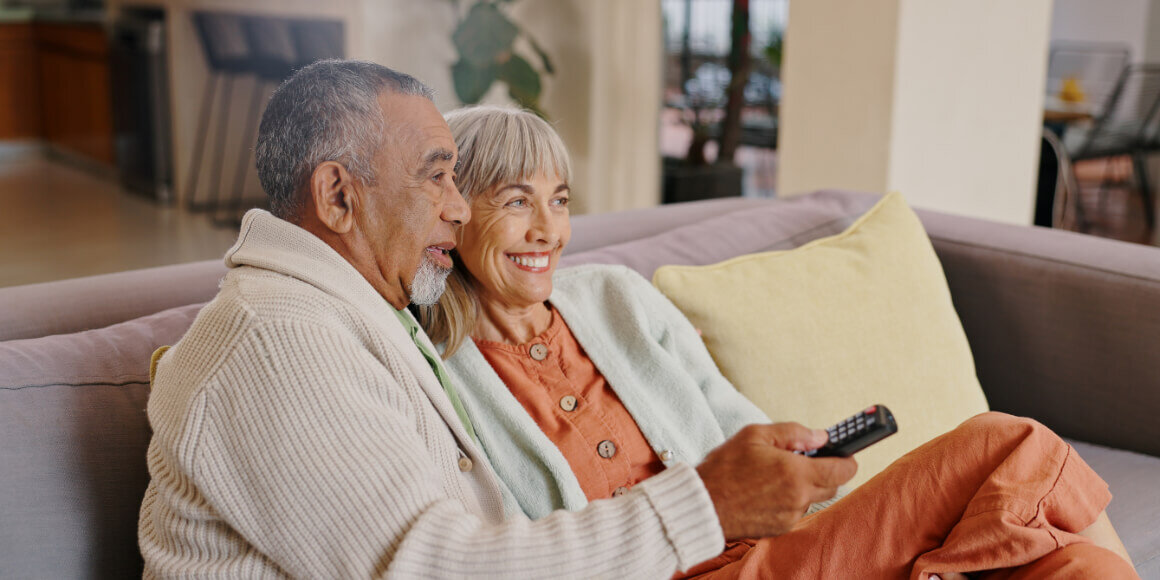 senior couple at home on the couch watching tv