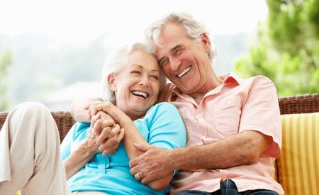 senior couple smiling and hugging on a couch