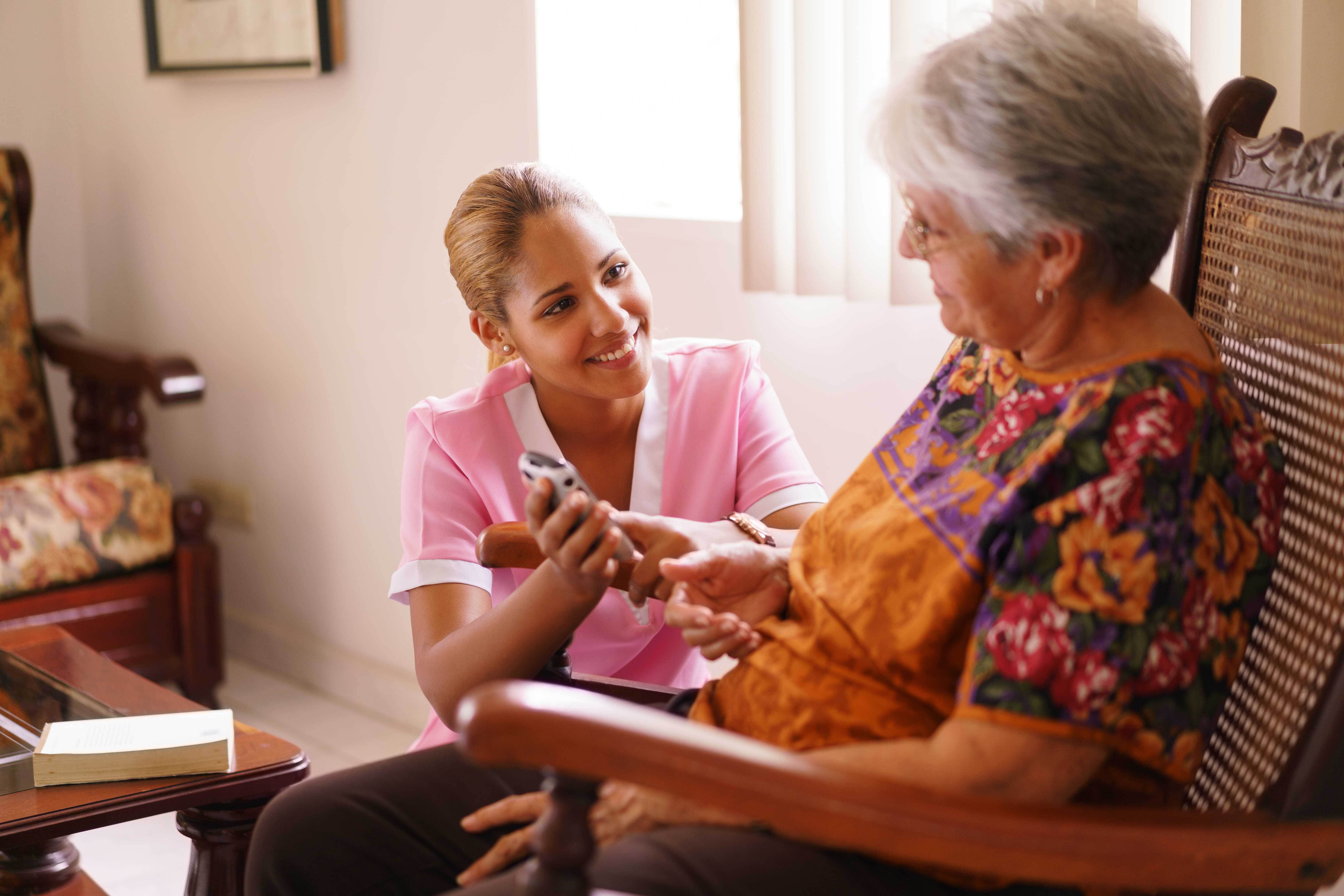 Woman in chair smiling with her hospice nurse