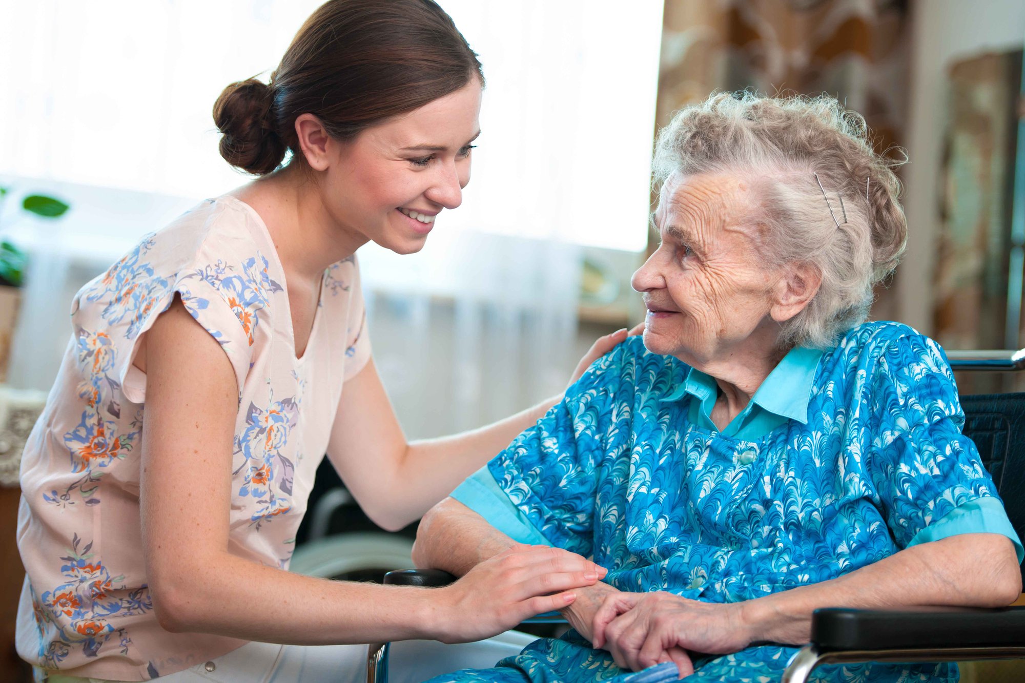 Daughter and older grandmother looking at one another smiling