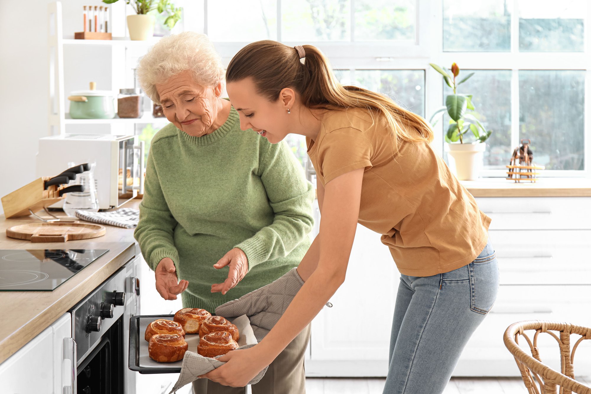 Daughter helping their mother in the kitchen taking food out of the oven