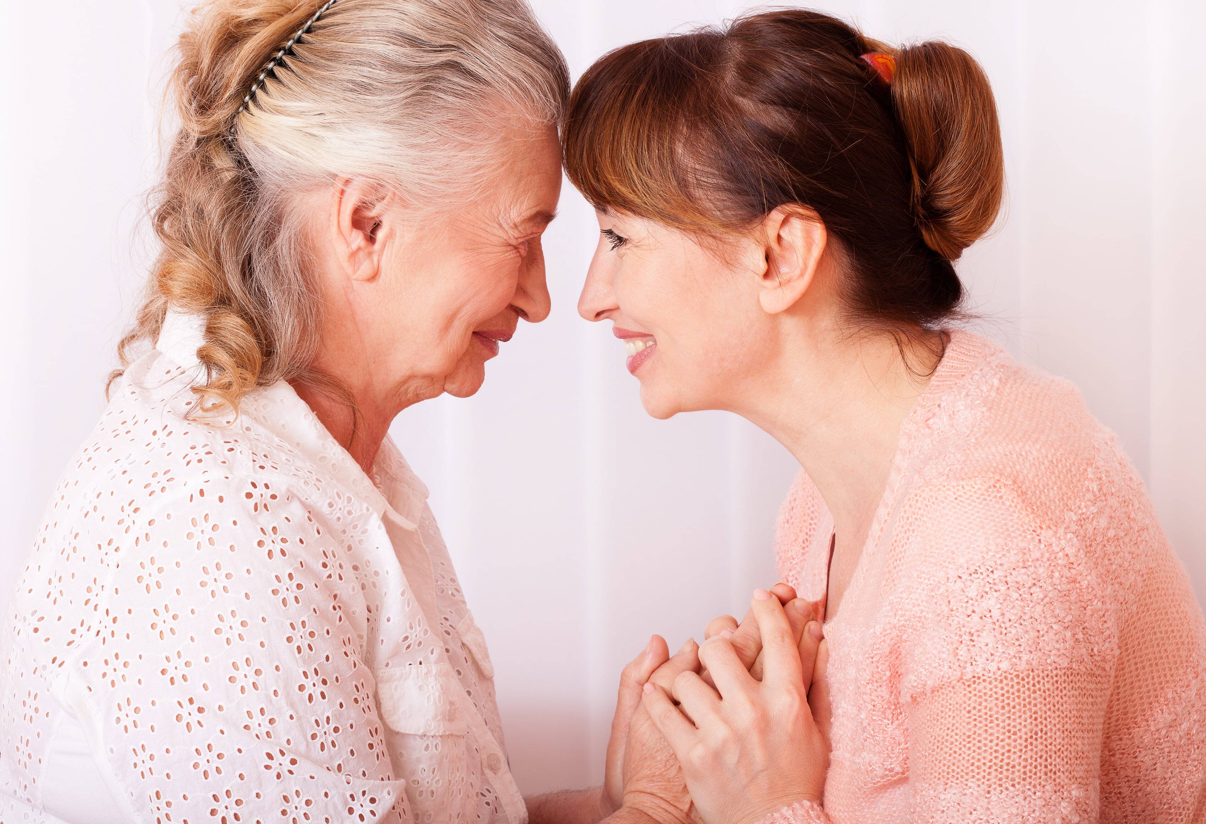 Mother and daughter touching foreheads and holding hands