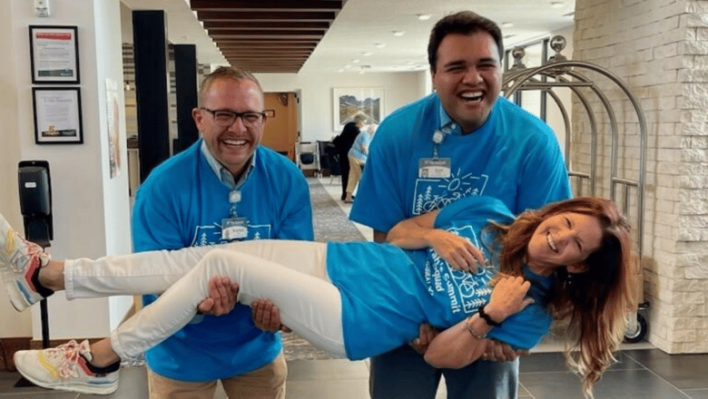 Two team members lifting another team member horizontally in their arms