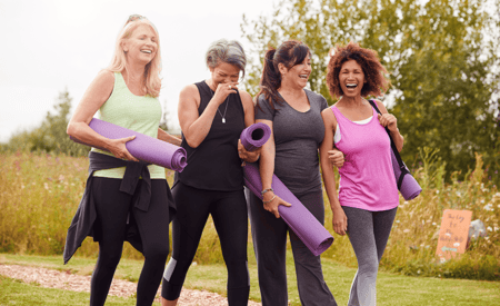 group of four senior woman walking with yoga mats