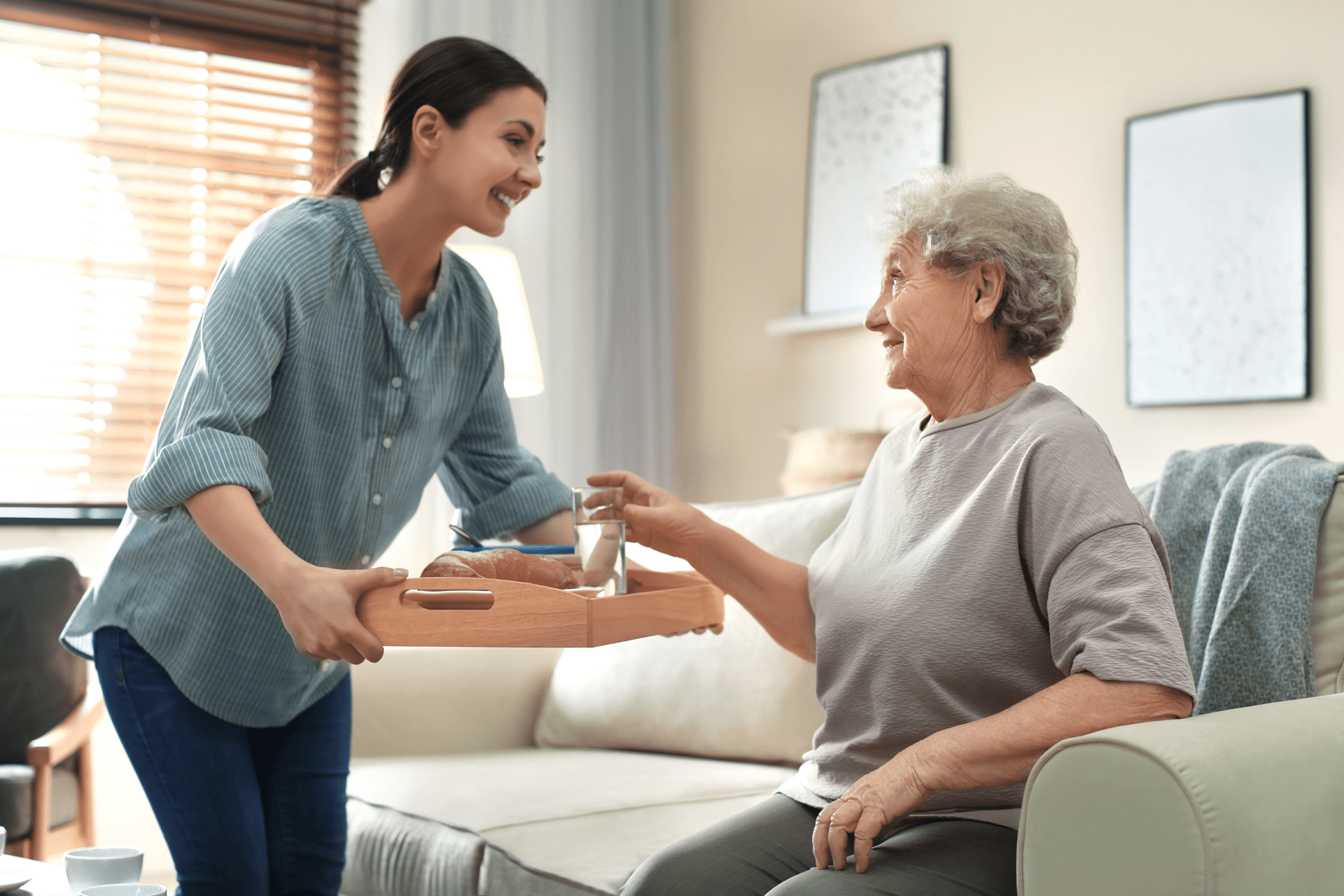 caregiver bringing water to a senior woman