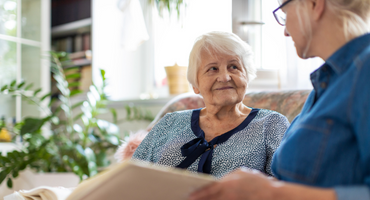 senior woman looking at photo album with daughter at adult day services